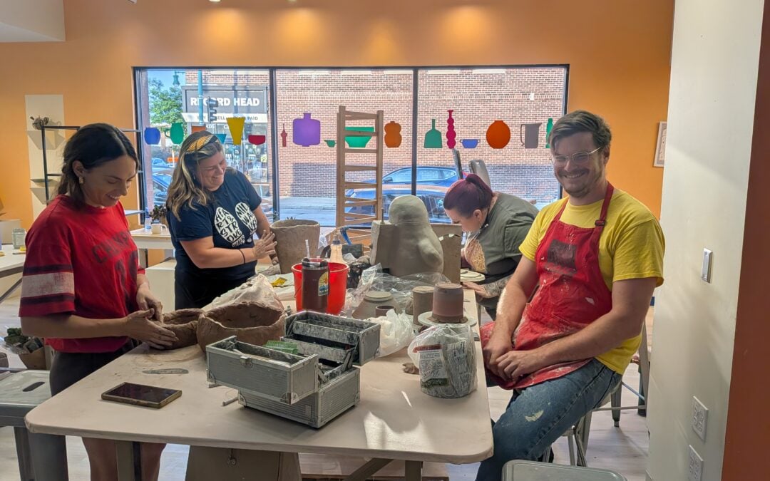 Group of students working at a table hand building with clay.